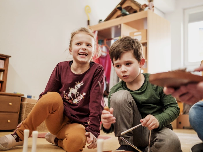 Zwei Kinder spielen lachend mit Musikinstrumenten im CJD, frühkindliche Förderung und musikalische Bildung.