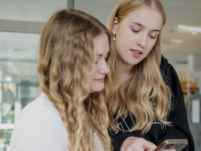 Zwei Jugendliche schauen auf ein Smartphone.