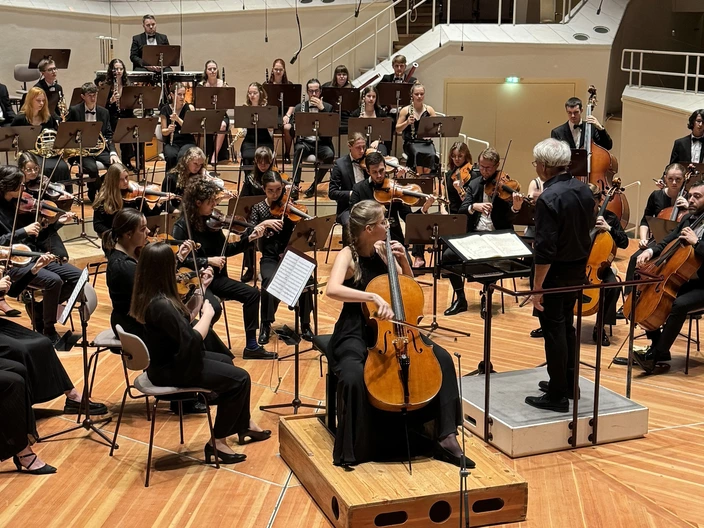 Ein großes Orchester musiziert unter der Leitung eines Dirigenten auf einer Bühne im Konzertsaal. Viele Musikerinnen und Musiker bringen gemeinsam ihr Können ein und schaffen ein beeindruckendes Klangerlebnis. Musik verbindet und fördert Talente – entdecke unsere musikalischen Projekte oder unterstütze junge Talente im CJD. Jetzt mehr erfahren oder mitmachen!