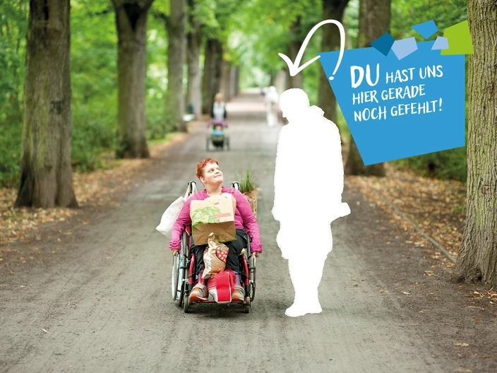  Eine Frau sitzt im Rollstuhl, sie hat Einkaufsbeutel auf Ihrem Schoß und zwischen ihren Beinen. Neben ihr ist eine weiße Lücke in Form eines Menschen. Darüber steht "Du hast uns hier gerade noch gefehlt!"