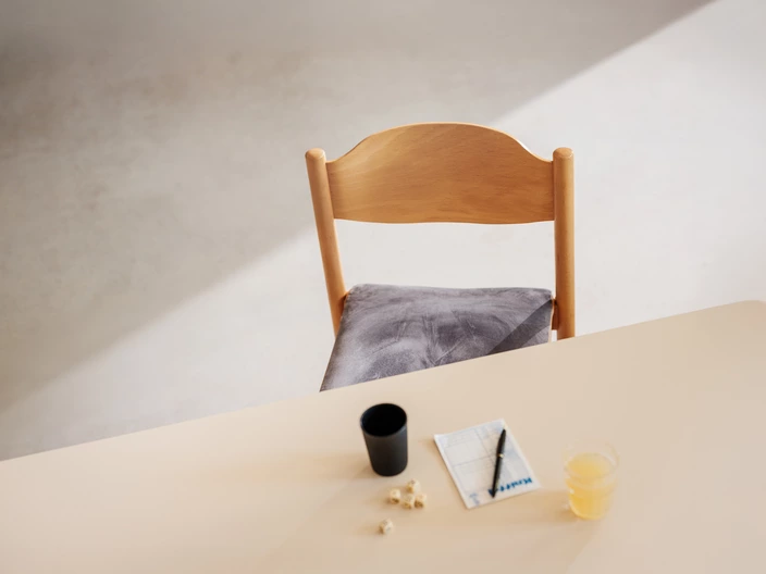 Einer leerer Stuhl an einem Tisch mit Kniffel-Becher und Kniffel-Würfeln vor sich.