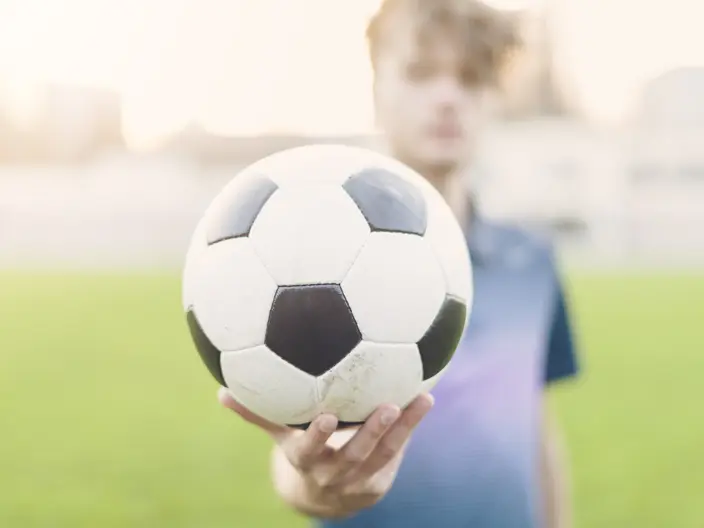 Eine Person hält einen Fußball in der Hand.